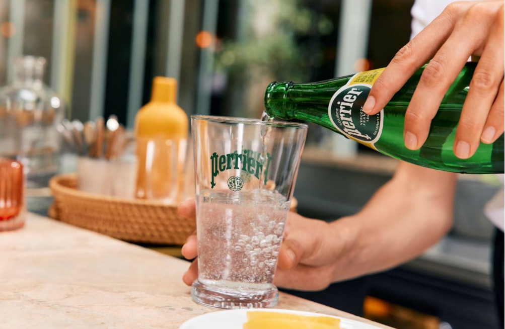 Pouring Perrier sparkling water into a Perrier glass